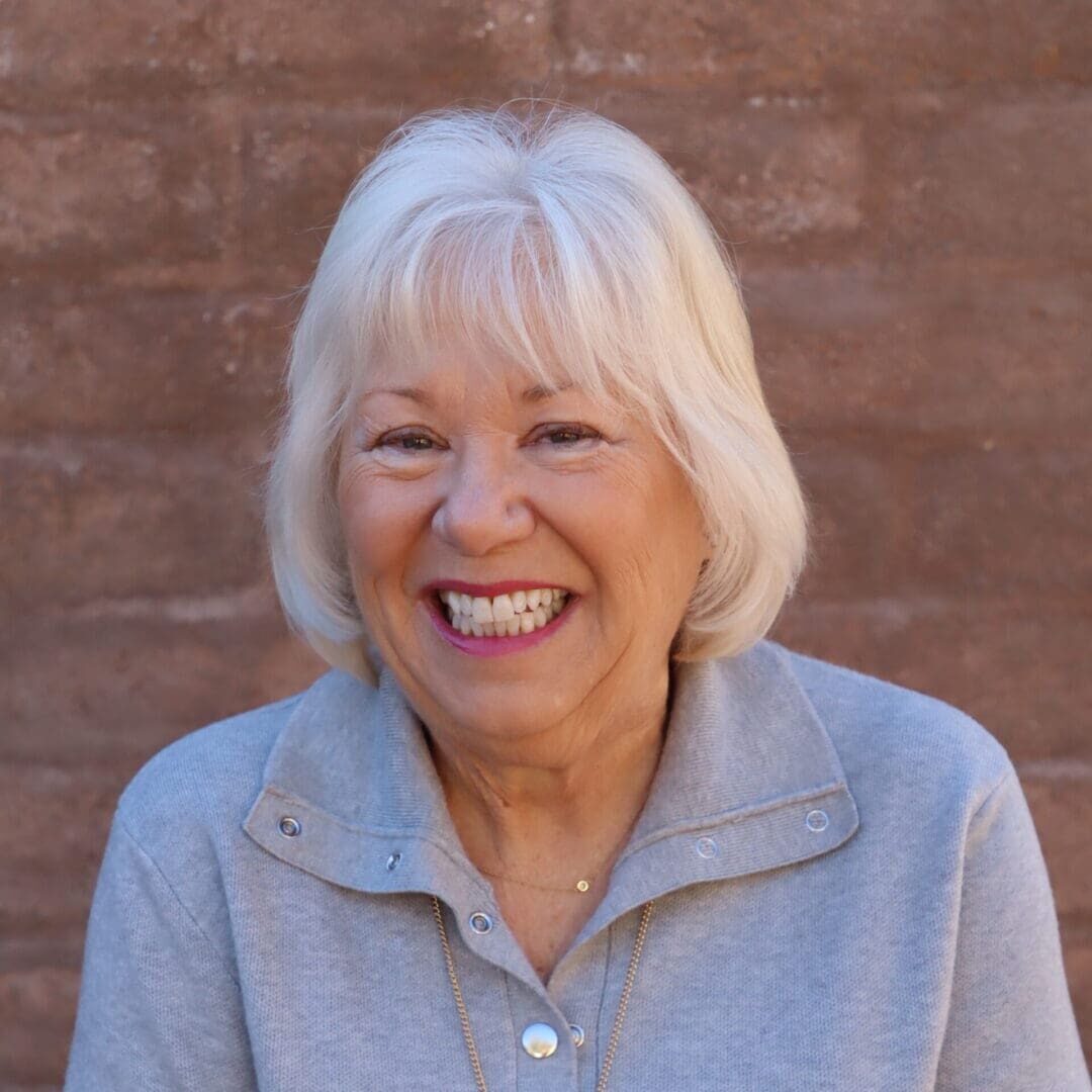 A woman with white hair smiling for the camera.